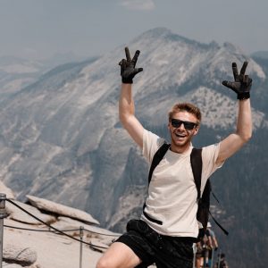 a man standing on top of a mountain with his hands in the air